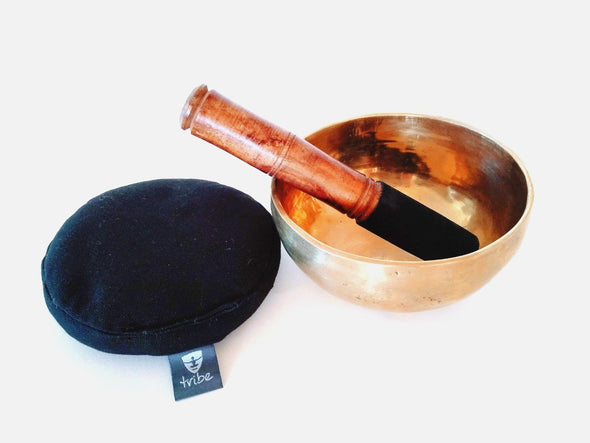 Tibetan Singing Bowl - brass bowl wooden striker inside bowl beside cotton pad | TRIBE Yoga
