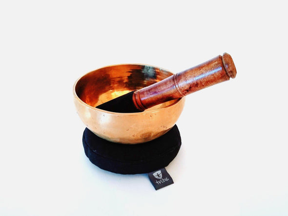 Tibetan Singing Bowl - brass bowl sitting on cotton pad with wooden striker inside bowl | TRIBE Yoga